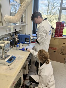 Videnskabelig assistent Nanna sidder på hug i laboratoriet, mens hun forklarer en gymnasieelev, hvad han skal gøre.