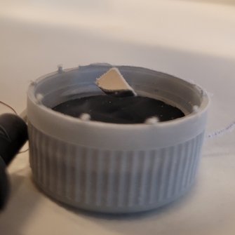 Billede af Meissner-effekte, hvor en lille magnet svæver over en superleder placeret i en lille plastikskål.