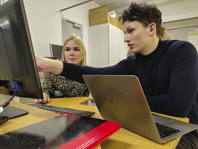 Forsker og gymnasieelev diskuterer resultater fra et forskningsværktøj på computeren.